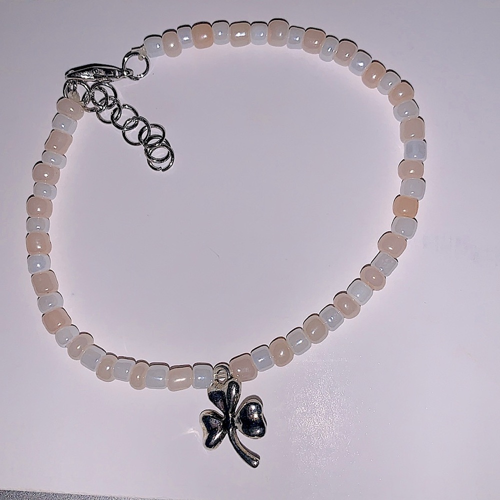 A cute three leaf clover bracelet/anklet that is white, and pastel pink